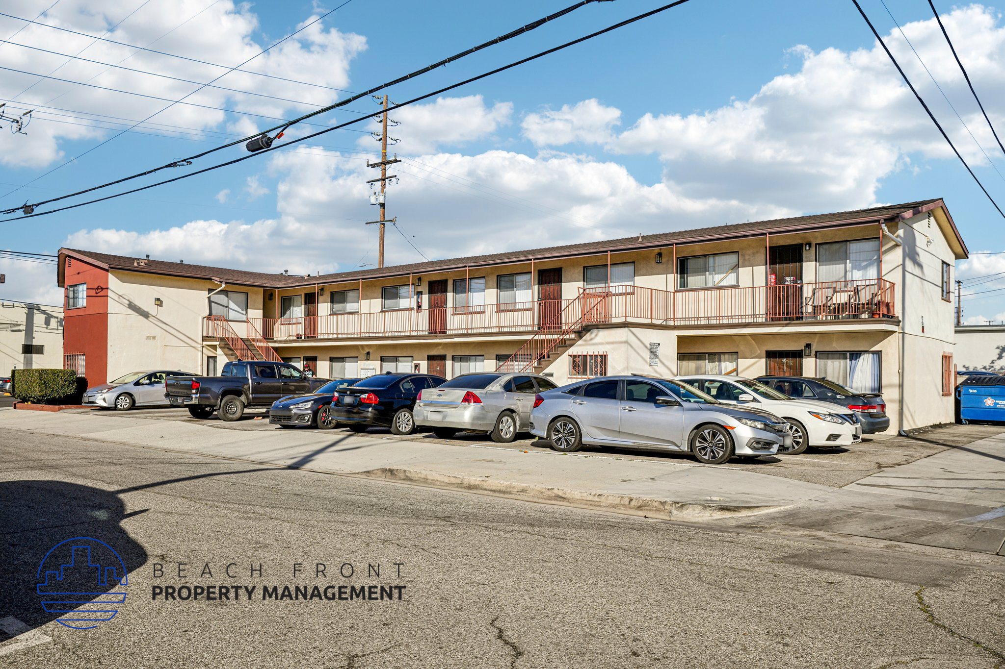 A parking lot with cars and a building with the words "BEACH FRONT PROPERTY MANAGEMENT" on it.
